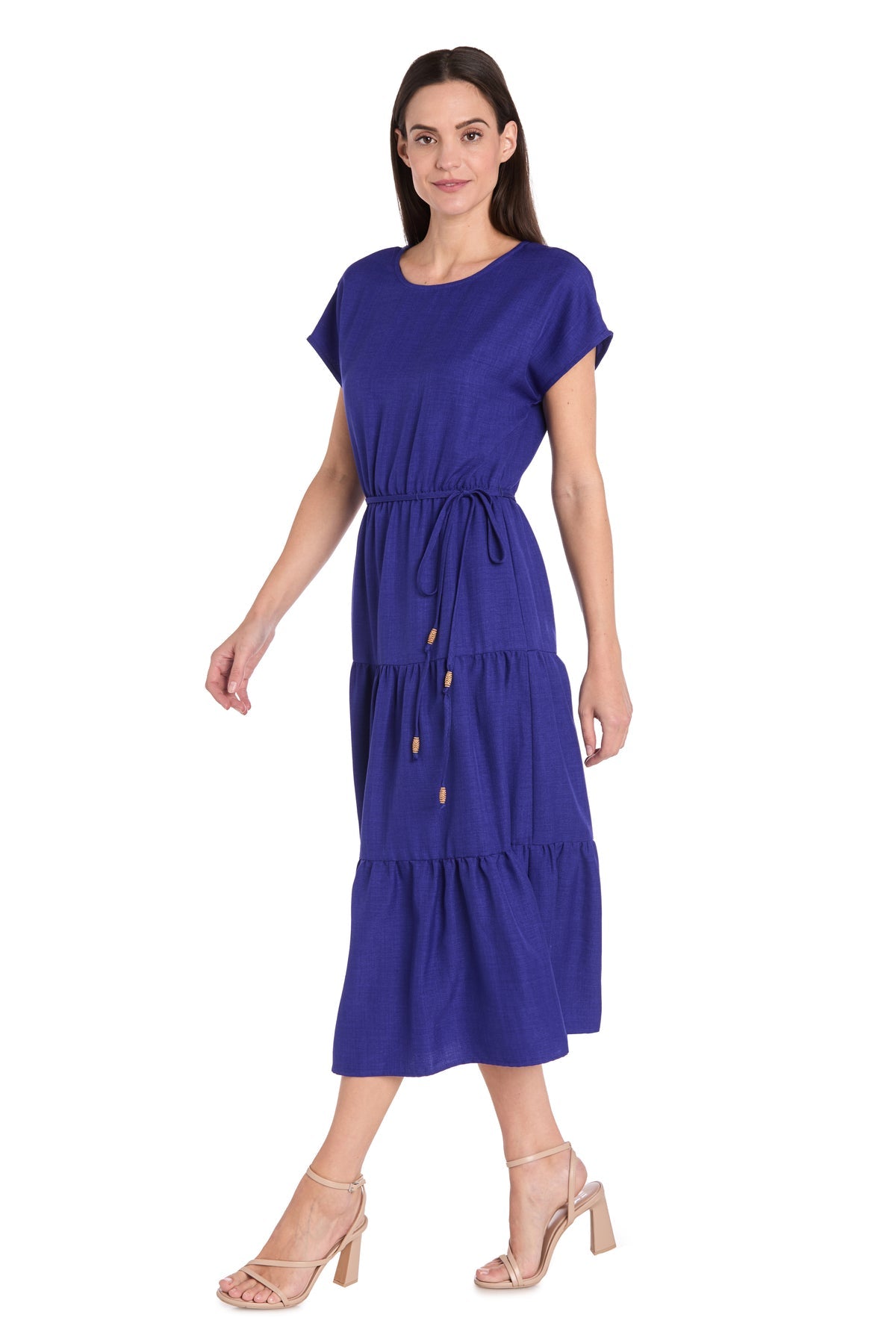 Woman wearing the R&M Richards 6680 Tea-Length Blue Party Dress with a waist tie and nude heeled sandals, standing against a white background.